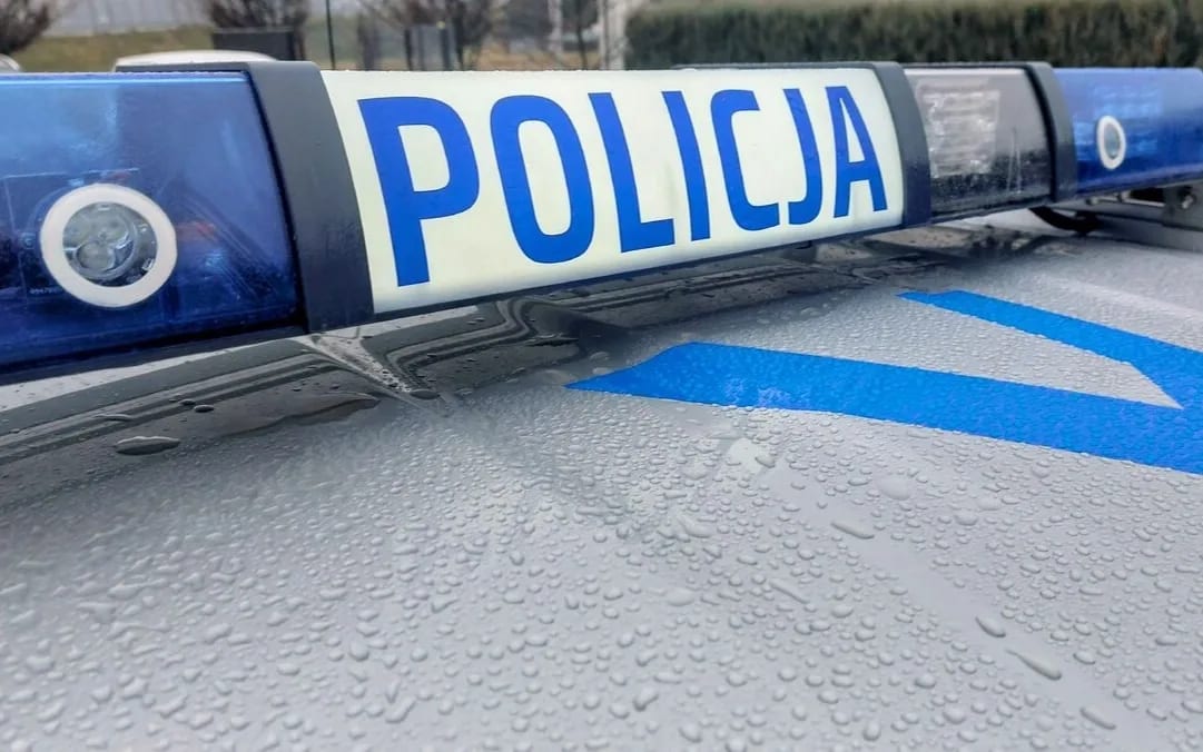 Dach policyjnego radiowozu pokryty deszczem, wyraźny napis policja