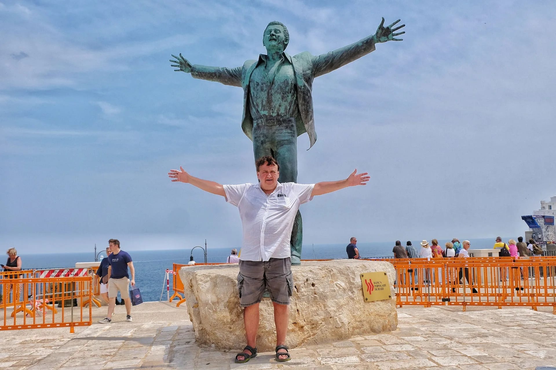 Turysta robi sobie zdjęcie pod pomnikiem Domenico Modugno w Polignano a Mare