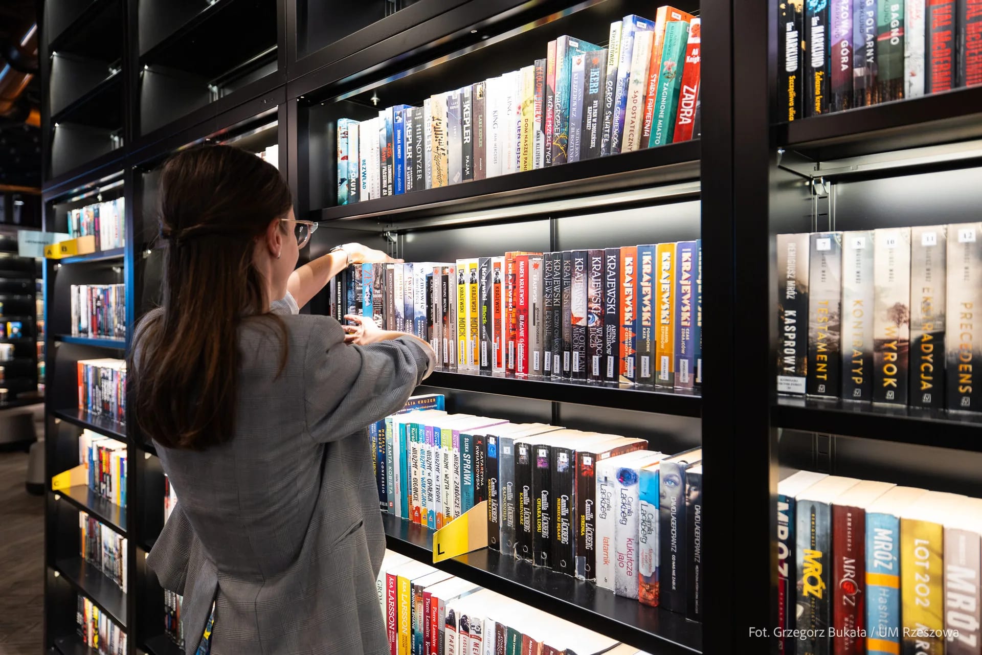 Pani bibliotekarka układa książki na półce