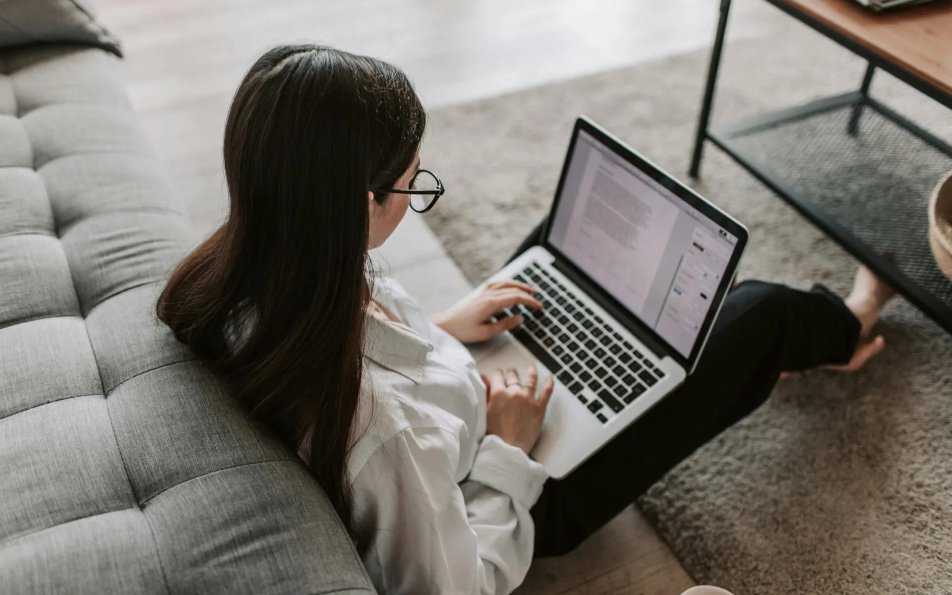 Studentka pracuj e na laptopie oparta o kanapę