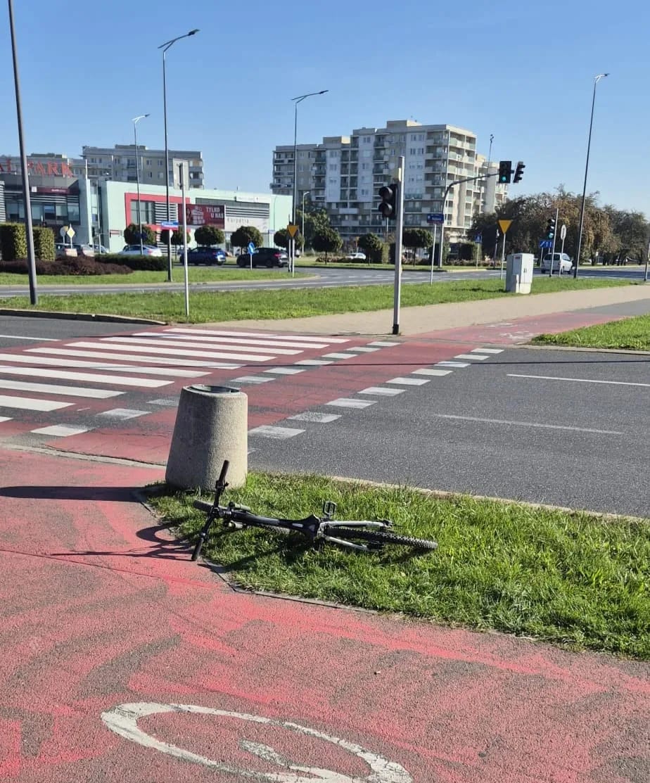 Rower leży przy skrzyżowaniu na poboczu ścieżki rowerowej
