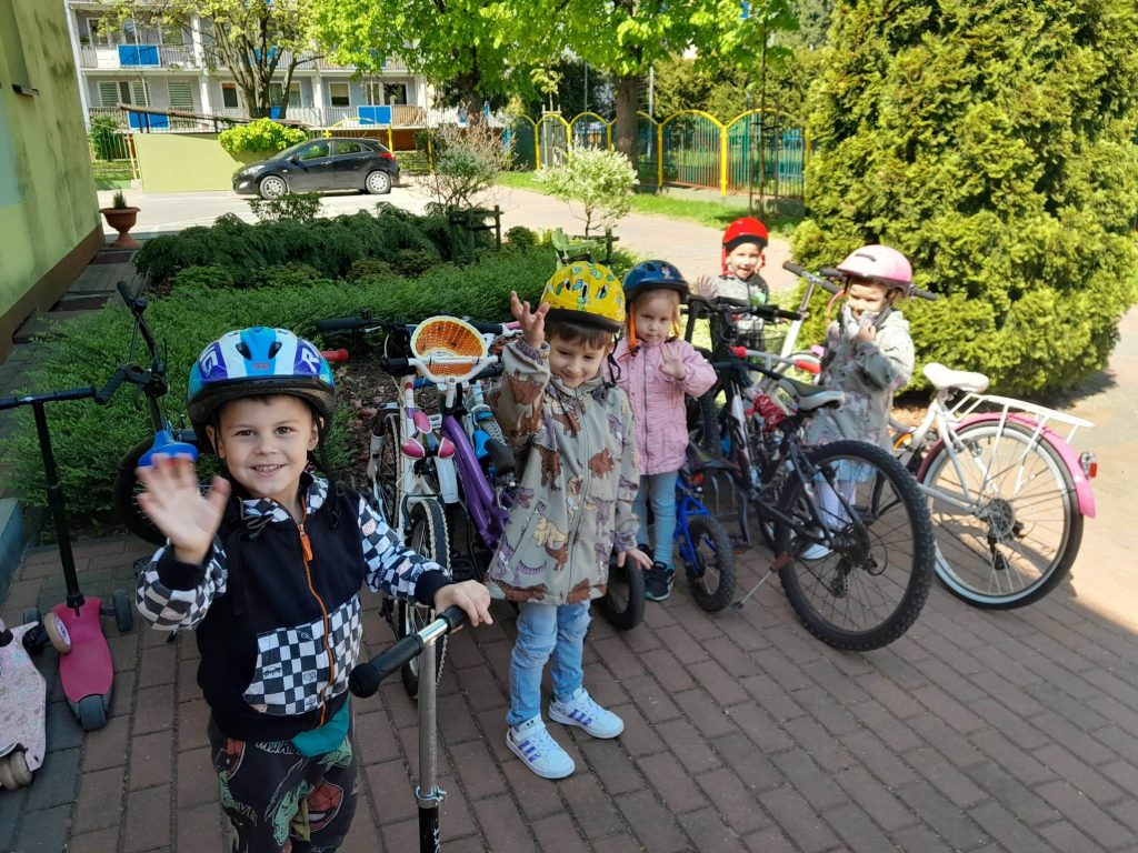 przedszkolaki na rowerkach i hulajnogach jada do przedszkola