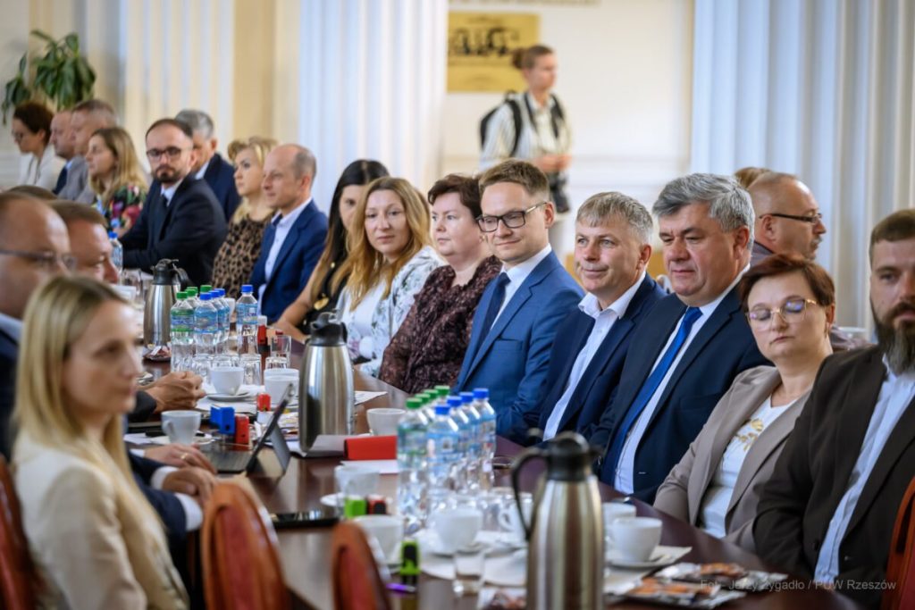 tłum ludzi siedzi w sali kolumnowej w urzędzie wojewódzkim