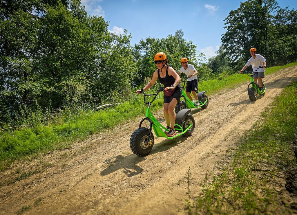 ludzie zjeżdżają z góry na górskich hulajnogach