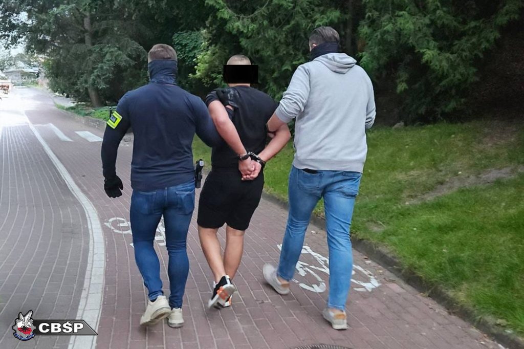 policjanci prowadzą zatrzymanego bandytę