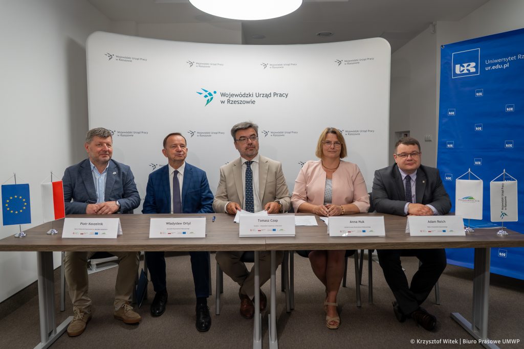 ludzie siedzą za stołem i podpisują umowę