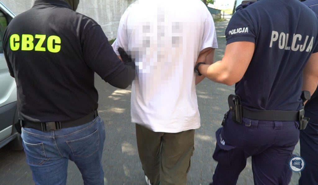 policjanci prowadza aresztowanego mężczyznę