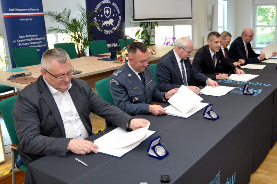 ludzie przy stole podpisują dokumenty