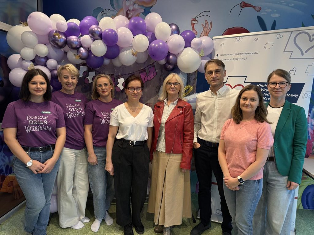 ludzie pozują na tle fioletowych balonów