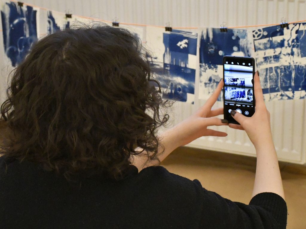 kobieta fotografująca swoją pracę telefonem