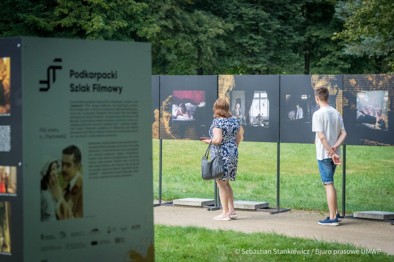 Ludzie oglądający plenerową wystawę dotyczącą filmowego dziedzictwa Łańcuta